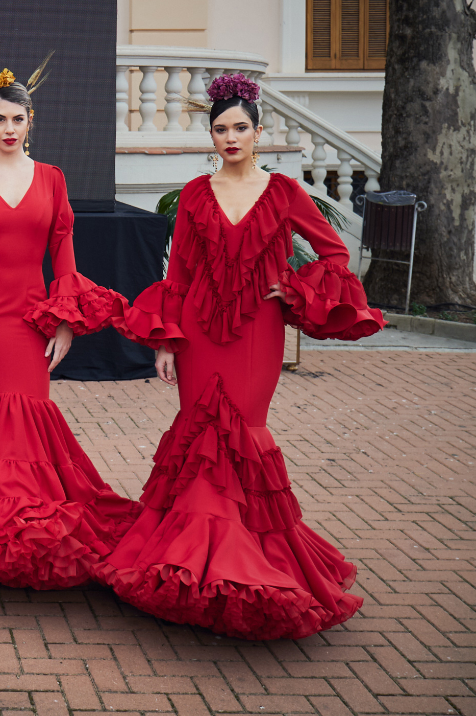 Vestido de flamenca rojo entallado en tejido elástico con manga de doble volantes y detalle de volante en gasa, escote en pico con volantes de gasa, la parte inferior del vestido esta compuesta por volante doble unido y volantes en gasa  y con una gran enagua de rizo en organdí.