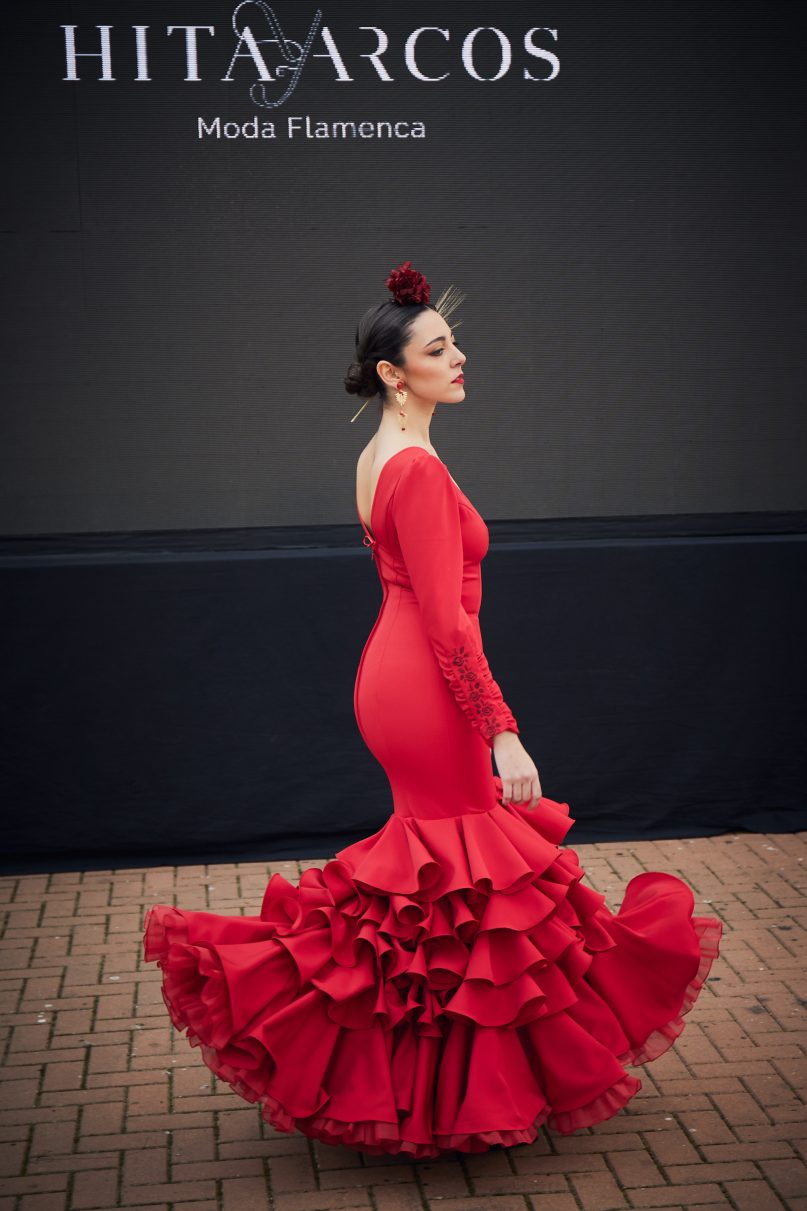 Vestido de flamenca rojo entallado en tejido elástico con manga en detalle rizado y un bordado en granate, la parte inferior del vestido esta compuesta por un conjunto de volantes medianos y uno final grande de gran volumen con organdí con rizo.
