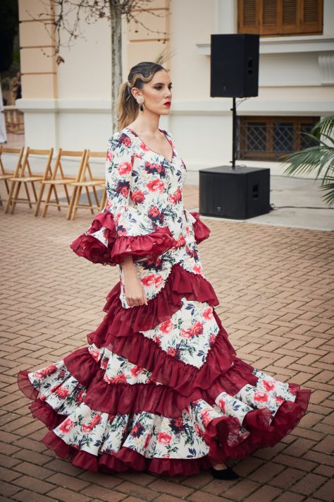 Vestido flamenca de nesgas blanco estampado, mangas con volantes y en la parte inferior volantes haciendo forma geométrica de rombo además de una gran volante con mucho volumen y rizos de organdí.