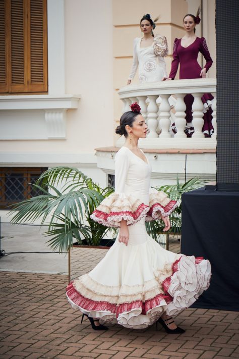 Vestido flamenca entallado en color crudo con mangas, volante grande con volantes pequeños en colores crudo, camel y granate. Con enagua amplia de rizo en organdí.