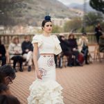 Falda flamenca en color crudo con bordados de rosa en granate y aplicación en cintura. tiene una juego de cuatro volantes medianos y uno mas amplio y voluminoso en el final con pasamanería de rizo en organdí.