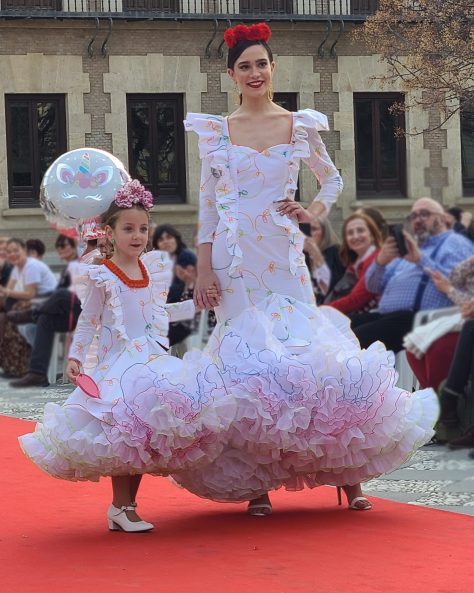 Vestido flamenca exclusivo algarabía en tejido de algodón bordado con hilo de colores, con manga larga, escote corazón delantero y cuadrado trasero, volante plisado en distintos tamaños como adorno sobre el cuerpo y volante grande en el inferior enagua clavel muy voluminoso blanco con el borde de colores