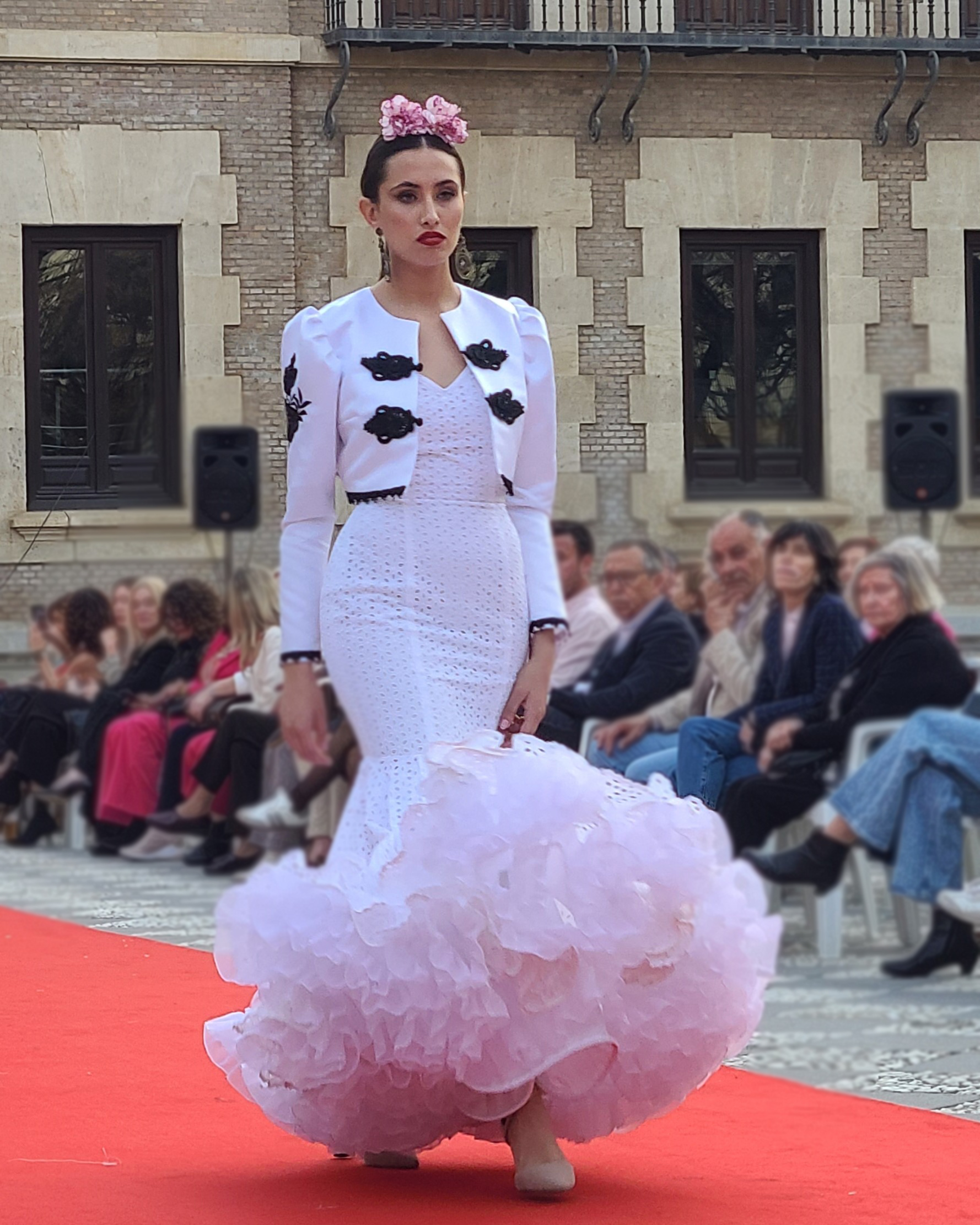 Vestido blanco en tejido perforado con un volante grande con volantito, sin mangas con escote delantero y trasero en pico profundo. Enagua de clavel en blanco muy voluminoso.