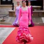 Vestido flamenca rosa chicle en tejido elástico, con manga lisa, escote delantero y trasero redondo y con volante grande en el bajo y volante pequeño como adorno