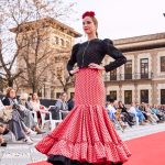 Vestido flamenca coral con lunar negro, escote delantero y trasero en redondo amplio y sin mangas. Volante amplio enganchado a otro volante de rizo en el bajo, enagua de tana