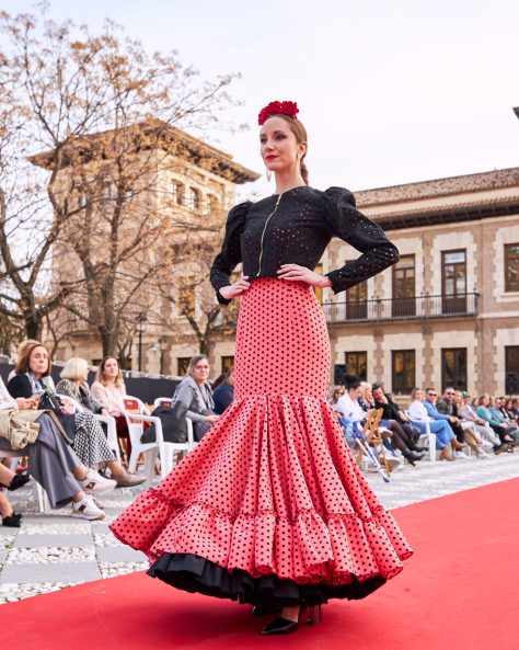 Vestido flamenca coral con lunar negro, escote delantero y trasero en redondo amplio y sin mangas. Volante amplio enganchado a otro volante de rizo en el bajo, enagua de tana