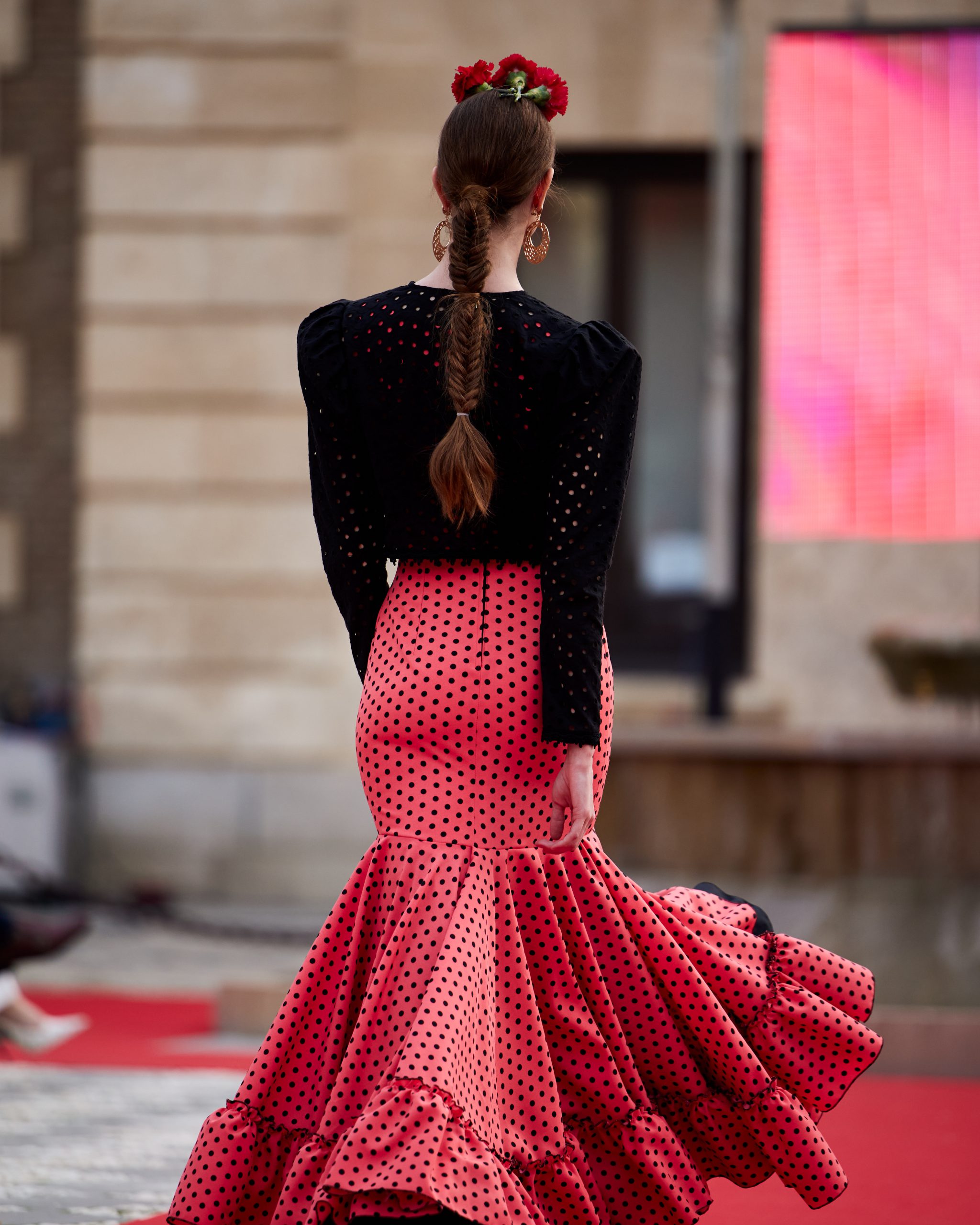 Vestido flamenca coral con lunar negro, escote delantero y trasero en redondo amplio y sin mangas. Volante amplio enganchado a otro volante de rizo en el bajo, enagua de tana