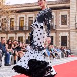 Vestido flamenca gris con lunar en negro, escote corazón con tirante de pasamanería, adorno de volante estilo péplum y con caída sobre la falda, volante grande en el bajo con enagua con vuelo.