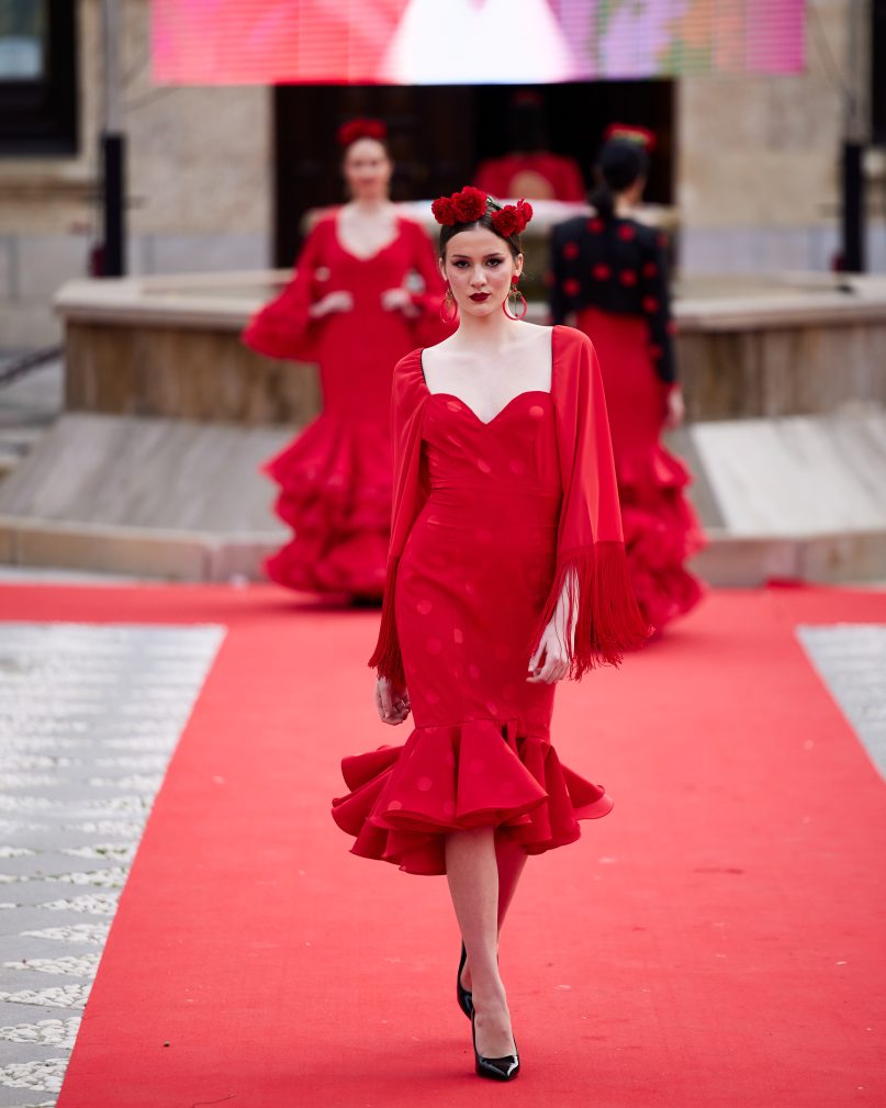 Vestido corto rojo, mangas amplias de gasa con flecos, palabra de honor en corazón. Volante grande en el bajo